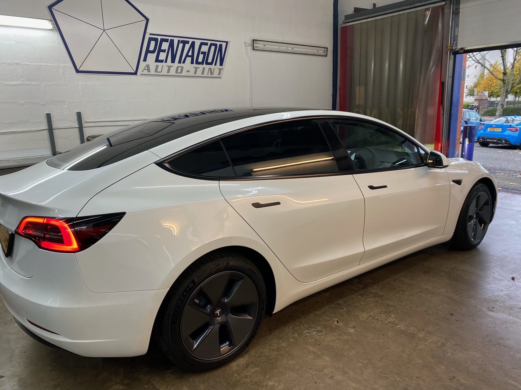 White Tesla in the shop for new tinted windows in Glasgow